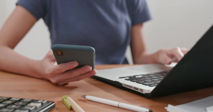 Woman work on laptop computer and use cellphone at home