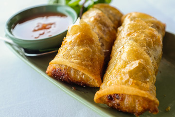 Close up thai fried spring roll and sweet chilli dip on green ceramic plate