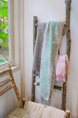 Cotton scarves on wooden ladder in a fashion shop with wooden chair and white wall background