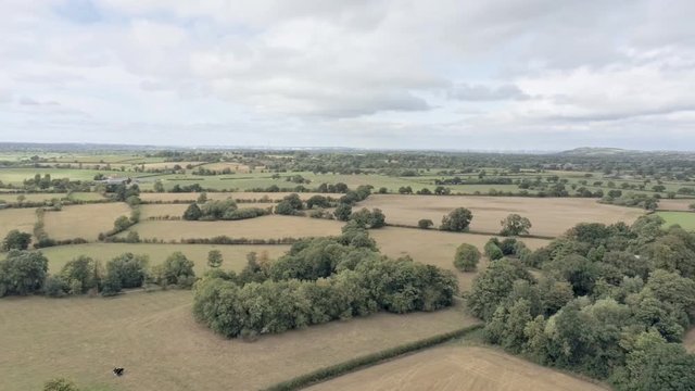 Aerial view, panning move. Cheshire plains panorama towards Merseyside in the distance. Roundabout near Tarvin