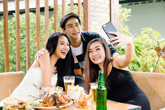 Asian Friends Having A Party In Home Making A Selfie. Happy Young People Taking Self Portrait During Party.