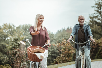 Naklejka premium Active lifestyle. Beautiful female person keeping smile on her face while sitting on her bicycle