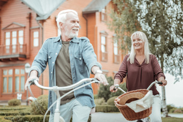Relaxed atmosphere. Positive delighted woman keeping smile on her face while following her husband