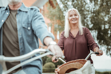 Have idea. Cheerful woman keeping smile on her face while riding bicycle