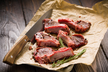 Raw lamb chops on a paper prepared for cooking on a rustic wooden table