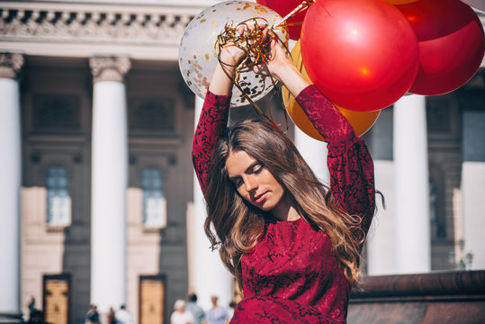 Beautiful woman in Red dress is so happy to walk with a lot of balloons