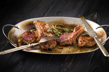 Lamb chops on a metal rustic plate with rosemary and spices