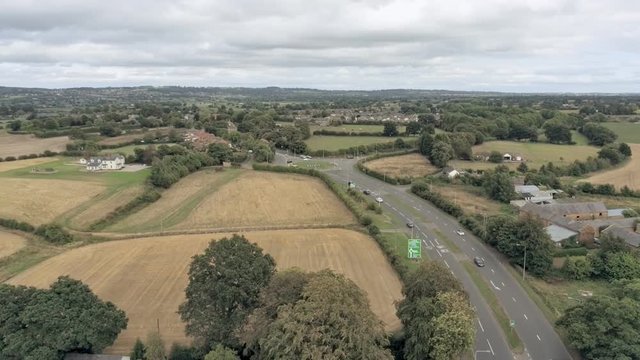 Aerial view, down move. Houses among trees, in background roundabout near Tarvin, town in Cheshire.