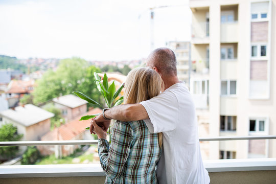 Middle Aged Couple Standing On Their New Apartment Terrace And Enjoying In Beautiful View. Real Estate And Moving Theme.