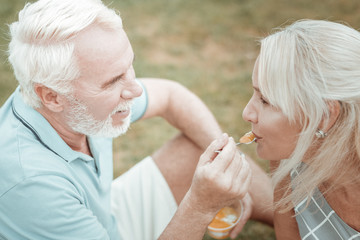 Time for dessert. Joyful male person sitting in semi position and looking at his partner