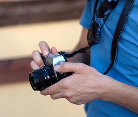 Close up, unrecognizable tourist man is holding an retro camera. Selective focus.