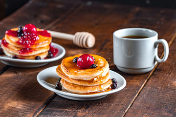 Fresh, homemade pancakes with honey, a cup of hot, fresh coffee on a wooden background. Tasty breakfast. Pancakes with syrup