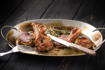 Lamb chops on a metal rustic plate with rosemary and spices