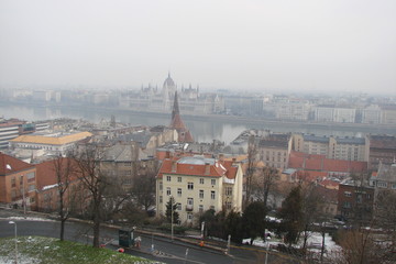 A view from the height of the observation deck of the Buda cities on the same bank of the Danube, and Pest on another remote bank of the Danube River against the background of the cloudy winter sky.
