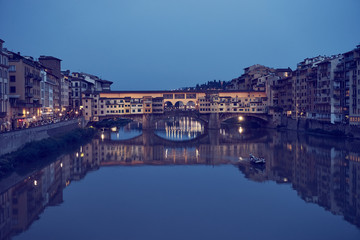 Famous bridge "Ponte Vecchio" in Florence in Italy at night / Illuminated bridge with nice reflections in the water
