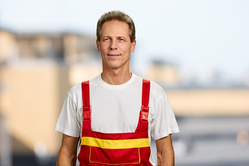 Smiling manual worker on blurred background. Portrait of caucasian middle-aged engineer. Handsome mature builder.