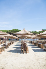 Albania. Golem. Beach shoreline with sun umbrellas made from straw. A blue sky on the Adriatic Sea.