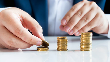 Conceptual image of financial and bank stability, Businessman putting coins in high stacks