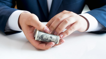 Closeup image of young man in suit holding big stack of US dollars in hands