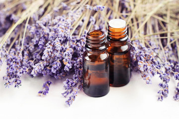 Dropper bottle of lavandula essential oil, bunch of dried purple lavender blossom white table....