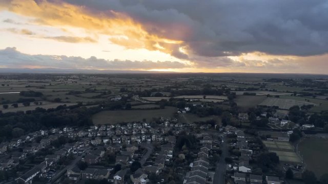 Aerial view, tilt up move. Dramatic sunset over residential area of small town, Tarvin in Cheshire.