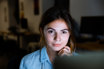 Young woman graphic designer using pc computer working at night in office.