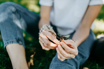 Woman sitting on the grass relaxing, holds a branch with bare feet