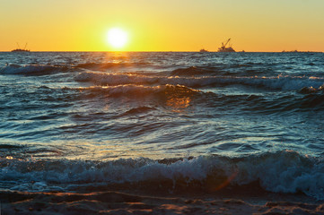 Sunset over the sea. Reflection of sunlight in the sea waves. Red and yellow sky in the rays of the sunset.
