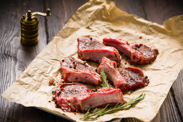Raw lamb chops on a paper prepared for cooking on a rustic wooden table.