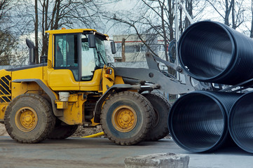 Forklift distributes plastic pipes of large diameter. Construction machinery at work.