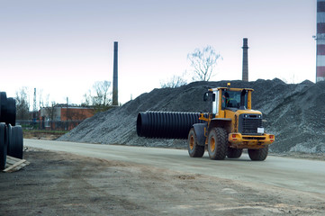 Forklift distributes plastic pipes of large diameter. Construction machinery at work.