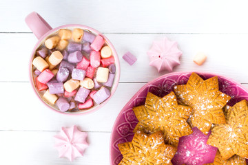 Christmas cocoa with marshmallow in a pink cup and ginger biscuit on a wooden table
