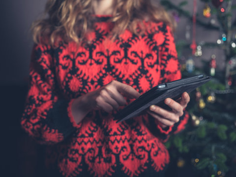 Woman using tablet by christmas tree