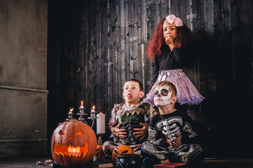Group of cute multiracial kids in scary costumes during Halloween party in an old house.