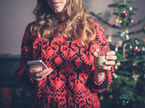 Woman with drink and smartphone at christmas