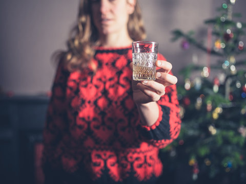 Woman having a drink by the christmas tree