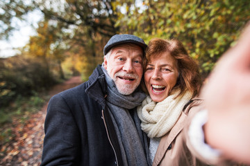 Senior couple in love in an autumn nature, taking selfie.