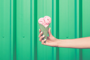 Female hand holding ice cream on green background