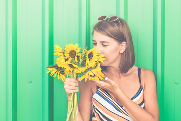 Pensive girl with sunflowers isolated on color wall.