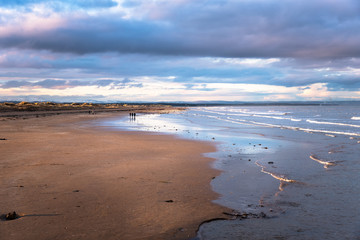 People Enjoying a Winter Sunset Strolling along a Beautiful Sandy Beach. St. Andrews, Scotland.
