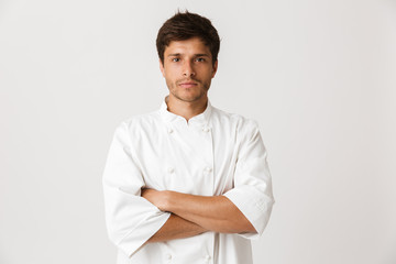 Young chef man standing isolated over white wall background looking camera.