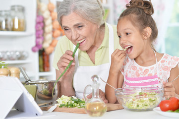 Portrait of grandmother and granddaughter preparing dinner