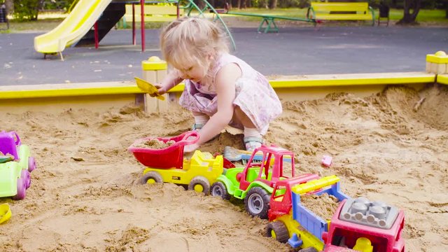 Three girls sitting in a sandbox and playing in the sand