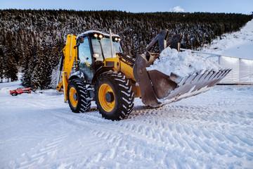 Bulldozer cleaning snow on mountain. Making road clean for car.