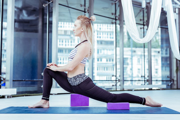 Fototapeta na wymiar Impressive results. Confident sportive woman stretching in studio while posing in profile