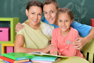 Fototapeta premium Portrait of mother with children doing homework