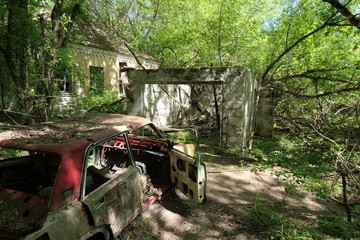 Abandoned house and a car wreck in the Chernobyl zone, Ukraine