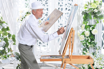 Portrait of senior man drawing picture in light room