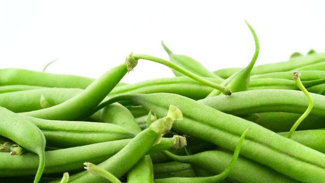 Side view of a green beans pile. Rotating on the turntable isolated on the white background. Close up. Macro.