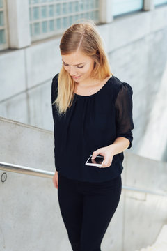 woman walking upstairs holding a mobile phone